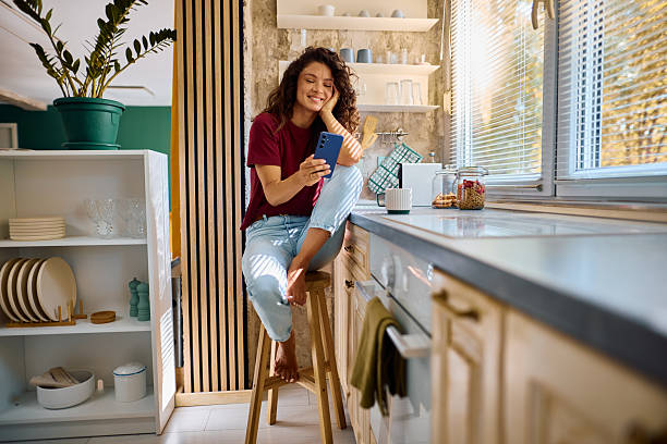 istock Young woman relaxing in kitchen using smartphone 2229088570