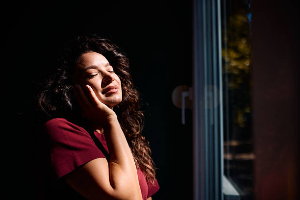 istock Serene woman enjoying sunlight by the window 2229088625