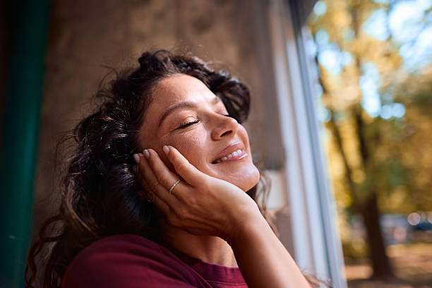 istock Serene woman enjoying sunlight by the window 2229088635