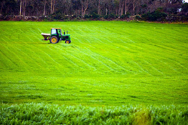 Tractor on large agricultural field, green grass. A Coruña province, Galicia, Spain