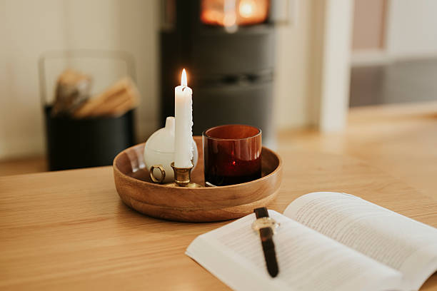 Candle light in front of fireplace with book and watch\nPhoto taken indoors