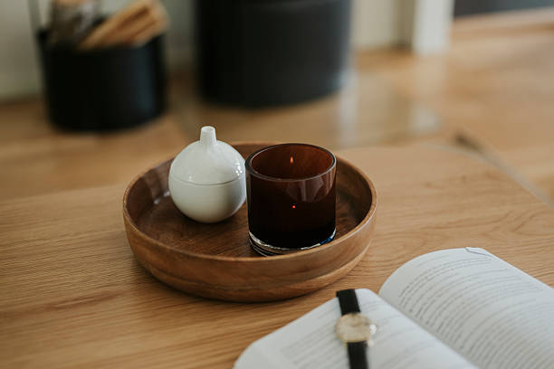 Candle light in front of fireplace with book and watch\nPhoto taken indoors