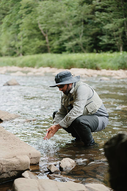 istock Fisherman washing hands in river while trout fishing 2229098617