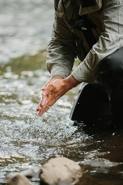 istock Fisherman washing hands in river while trout fishing 2229099489
