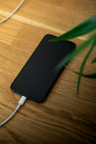 istock Smartphone charging on wooden table at home 2229100075