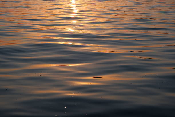 Stunning sunset over the Adriatic Sea captured from the coastline of Zadar, Croatia. The sky glows with vibrant hues of orange, pink, and purple, reflecting beautifully on the calm water. Silhouettes of ancient architecture, boats, and the famous Zadar Sea Organ add depth and character to the scenic view. Perfect for travel, nature, landscape, and European destination concepts.