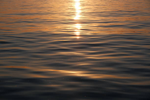 Stunning sunset over the Adriatic Sea captured from the coastline of Zadar, Croatia. The sky glows with vibrant hues of orange, pink, and purple, reflecting beautifully on the calm water. Silhouettes of ancient architecture, boats, and the famous Zadar Sea Organ add depth and character to the scenic view. Perfect for travel, nature, landscape, and European destination concepts.