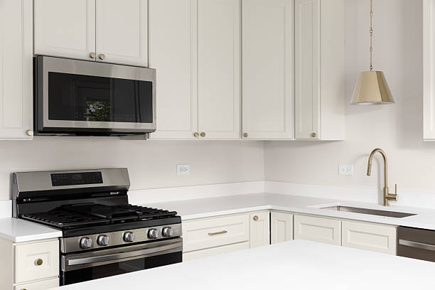 An off white kitchen with white countertops and gold accents.