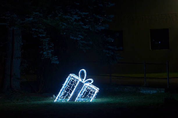 In the serene darkness of night, two glowing presents are beautifully sitting among the grass, creating a magical atmosphere beneath the stars