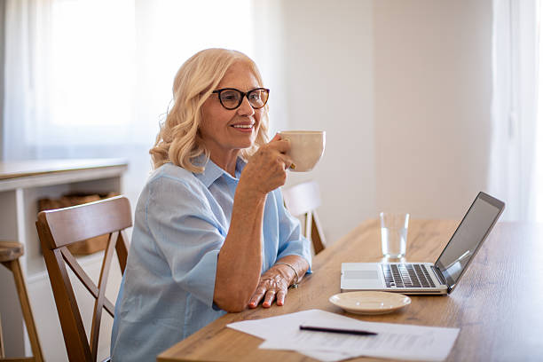 istock Senior adult woman drinking coffee while working from home 2229118003