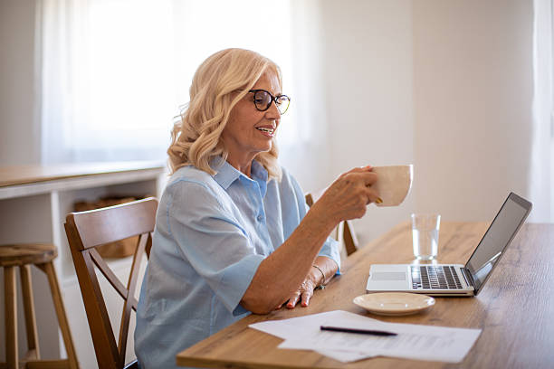 istock Senior adult woman drinking coffee while working from home 2229118418