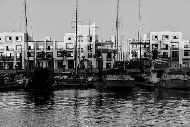 A black and white photo of boats lined up in the harbor of Marina Agadir beach, Morocco