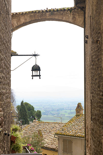 Elevated view from Assisi over olive groves and medieval rooftops toward the Umbrian plain and distant hills, Umbria, Italy.