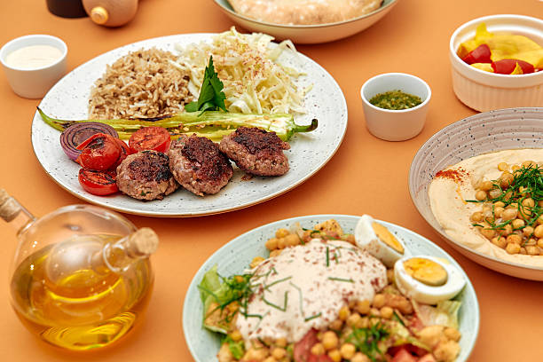 A Beautiful Spread of Mediterranean Cuisine Featuring Grilled Meat Patties, Flavorful Hummus, Fresh Vegetables, and Aromatic Rice, Perfect for a Nutritious Meal stock photo