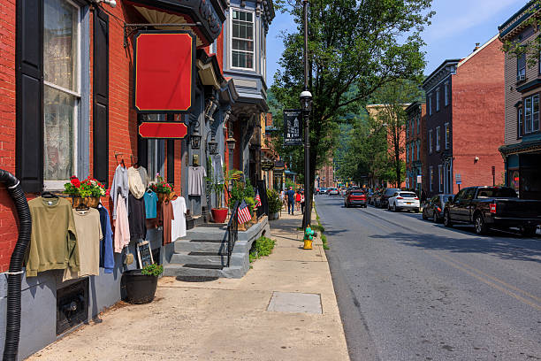 istock Retail clothing display outside storefront on main street. Pedestrians strolling through picturesque downtown district surrounded by mountains. 2229125367