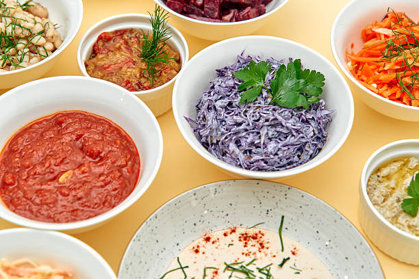 istock A Vibrant Array of Colorful Dishes Displayed in Bowls Featuring Fresh Vegetables, Creamy Sauces, and Savory Salsas on a Yellow Background 2229127119