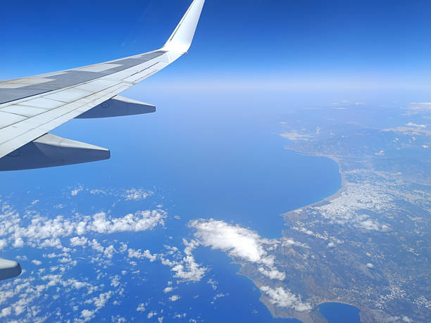 Aerial view from airplane window over the Mediterranean coast with wing in frame