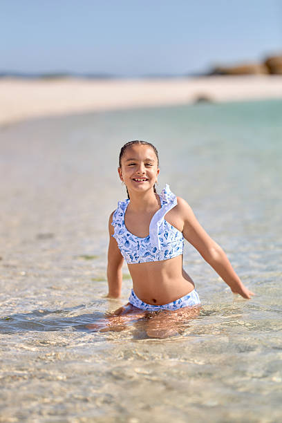 istock Child enjoying a sunny day on the beach while playing in clear shallow water 2229128629