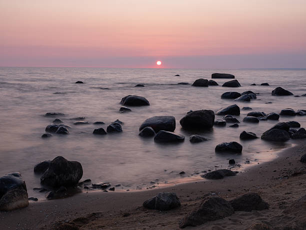 sunset and sandy beach with big stones in summer