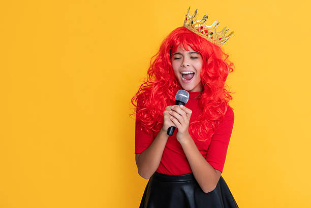 istock kid smile in crown with microphone on yellow background 2229131147