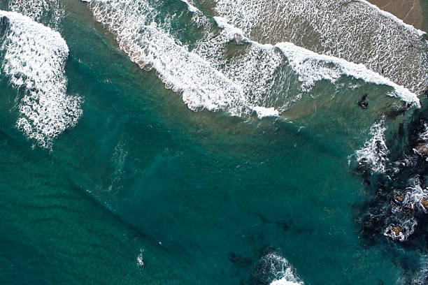 istock A Dynamic Seascape with Foamy Waves and a Rocky Beach, aerial top down drone view 2229132342