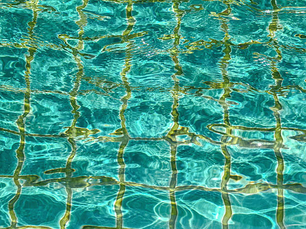 Pool with clear water is lined with blue-green tiles. Calm water is reflected in tile and creates serene atmosphere