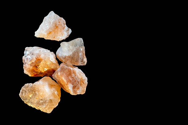 Aerial view of large stones of pink Himalayan salt, placed on a black surface. Close up studio shot, no people.