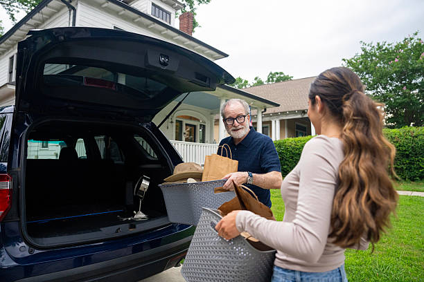 istock Senior man receiving assistance from his adult daughter while loading boxes into car trunk. 2229135814