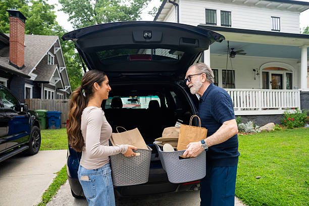 istock Senior man receiving assistance from his adult daughter while loading boxes into car trunk. 2229135888