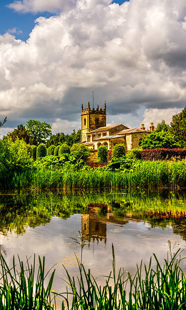 istock Historic English Church Reflected in Serene Pond Under Dramatic Skies 2229136865