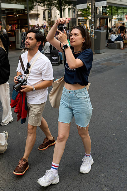 Young tourists taking pictures while walking down a busy city street during their vacation