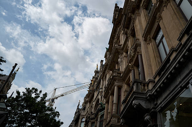 Construction crane rising above a historic building under partially cloudy sky in antwerp, belgium