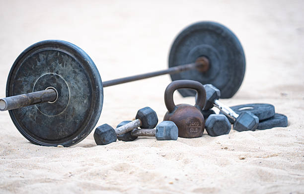 Kettlebell and weights background. Bodybuilding with heavy weights. Park workout with dumbbells. Sports scene with weights. Kettlebell, dumbbells and barbell background. Weights training on the beach