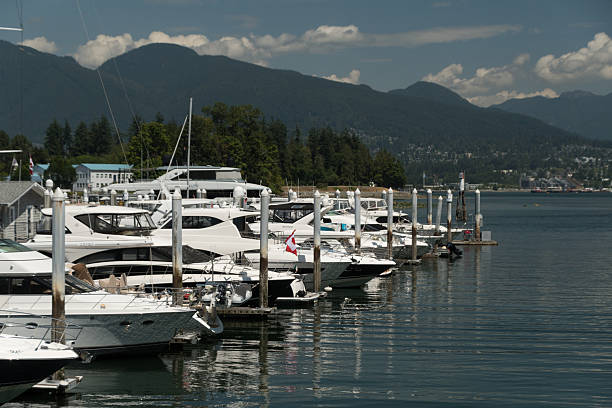Row of luxurious upscale yachts in Coal harbor marina leading to North Shore Mountains in the background