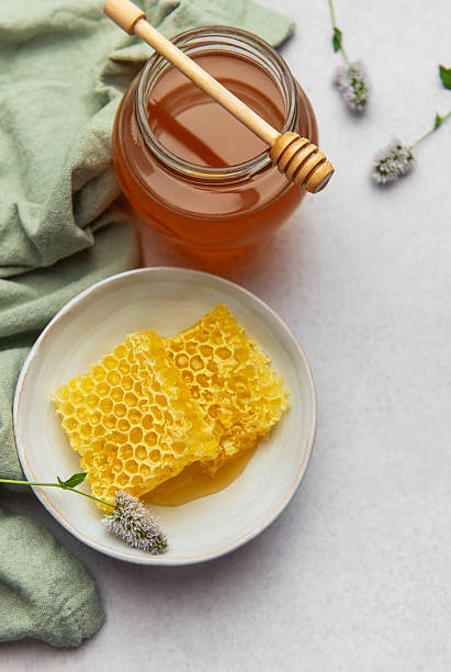 istock Honeycomb and honey jar with wooden dipper on kitchen table 2229173391