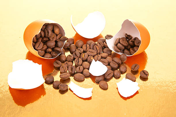 istock A broken egg with coffee beans spilling out on a golden surface, surrounded by scattered eggshells, creating a surreal and creative composition for food and beverage themes 2229175035