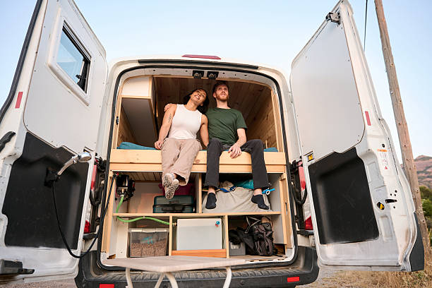 istock Young couple relaxing in their converted van at sunset 2229178154