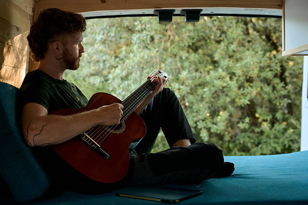 istock Musician playing acoustic guitar in camper van 2229178202