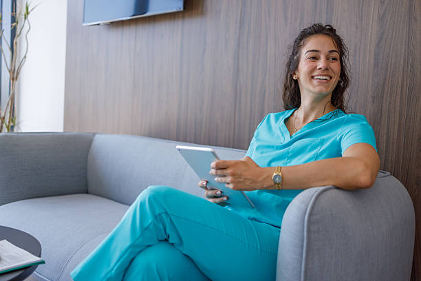 istock Smiling doctor using digital tablet sitting on sofa in hospital waiting room 2229178276