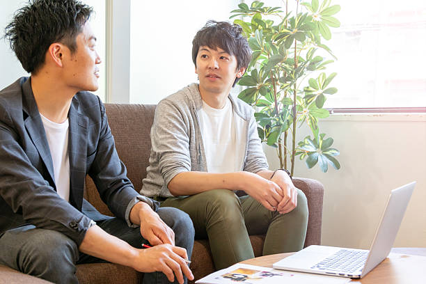 istock Two Japanese Men Sitting on a Sofa and Talking 2229182363