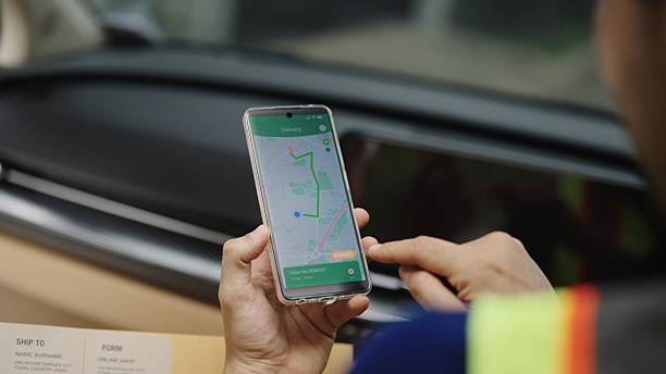 istock Close up delivery man hand holding smartphone with a tracking mobile application  while handling a package card box go on delivering postal parcel 2229182427