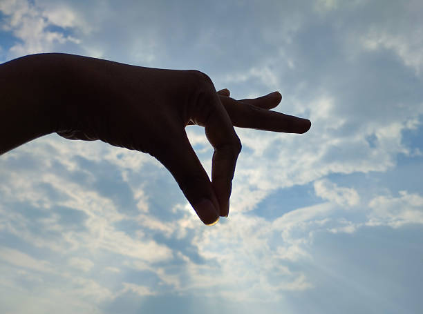 istock Hand Gesture Silhouette Framed Against a Cloudy Sky 2229183677