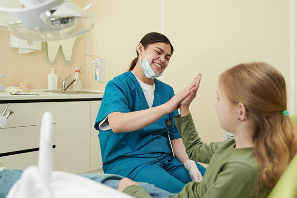 junge zahnärztin, die einem lächelnden kindpatienten high five gibt - nurse high five mask stock-fotos und bilder
