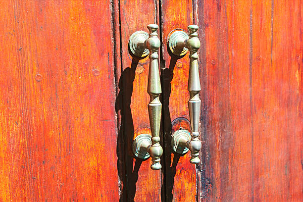 Weathered wooden doors, accented by antique metal handles. Aged door with elegant antique style handles