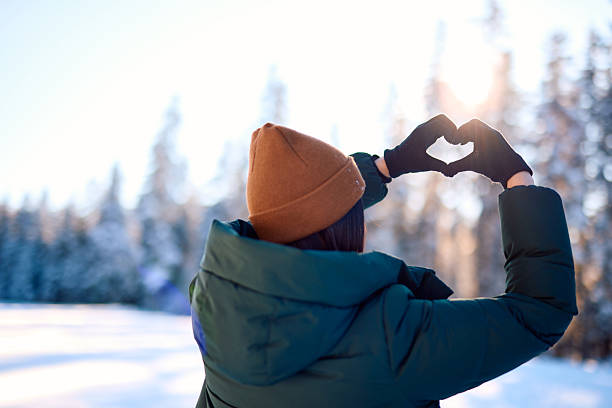 istock Woman making heart shape with hands in snowy forest 2229187958