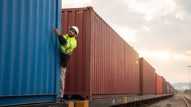 istock Foreman checking inventory or task details on freight train cars and shipping containers. Logistics concept, import, and export industries. 2229191551