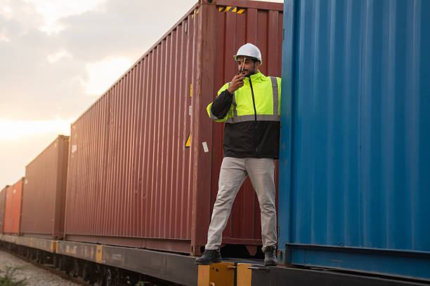 istock Foreman checking inventory or task details on freight train cars and shipping containers. Logistics concept, import, and export industries. 2229191647