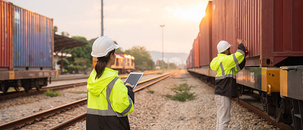 istock Foreman checking inventory or task details on freight train cars and shipping containers. Logistics concept, import, and export industries. 2229191785