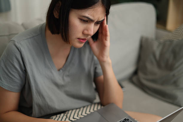 istock Asian woman working on laptop with stressed expression on sofa at home 2229192209
