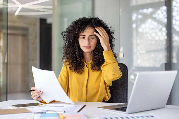 istock Anxious businesswoman examines documents, contemplating her work with a look of concern on her face. 2229195516